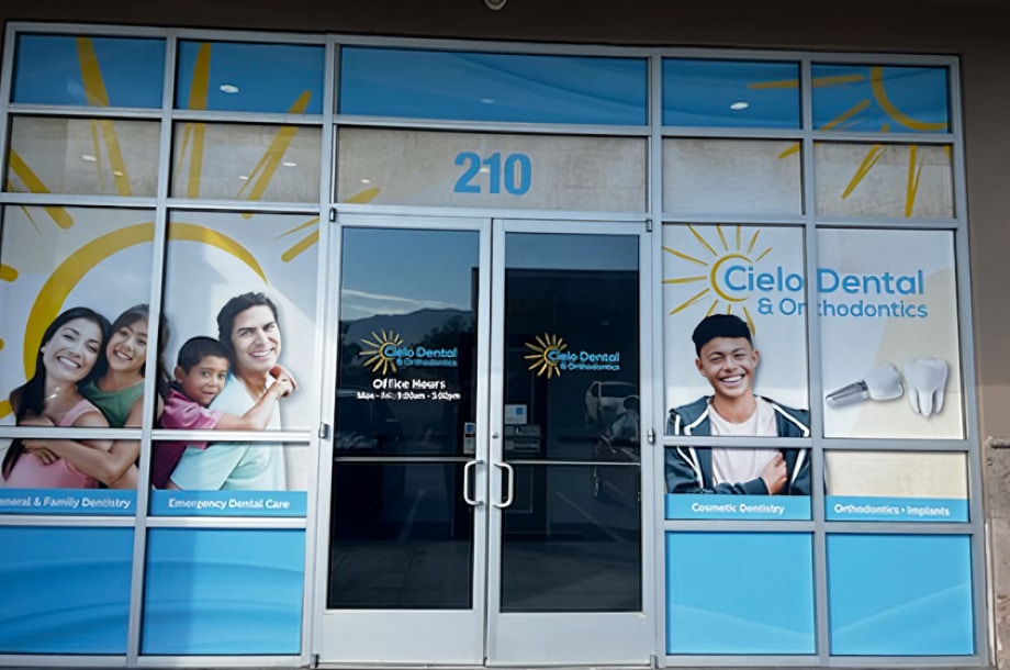 Cielo Dental & Orthodontics storefront with glass doors, windows displaying patient smiles and dental imagery, suite 210.