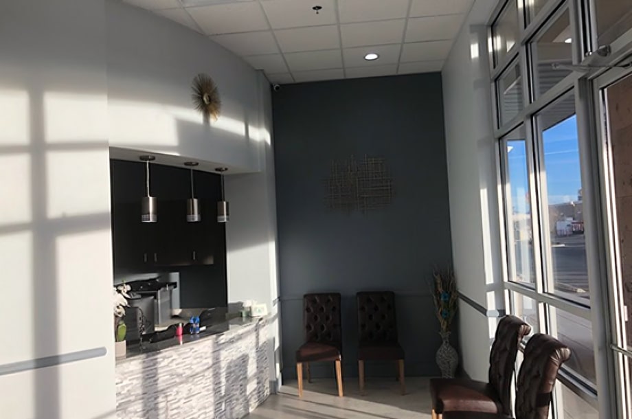 Modern dental office interior with reception area, dark accent wall, and bright natural lighting from windows.